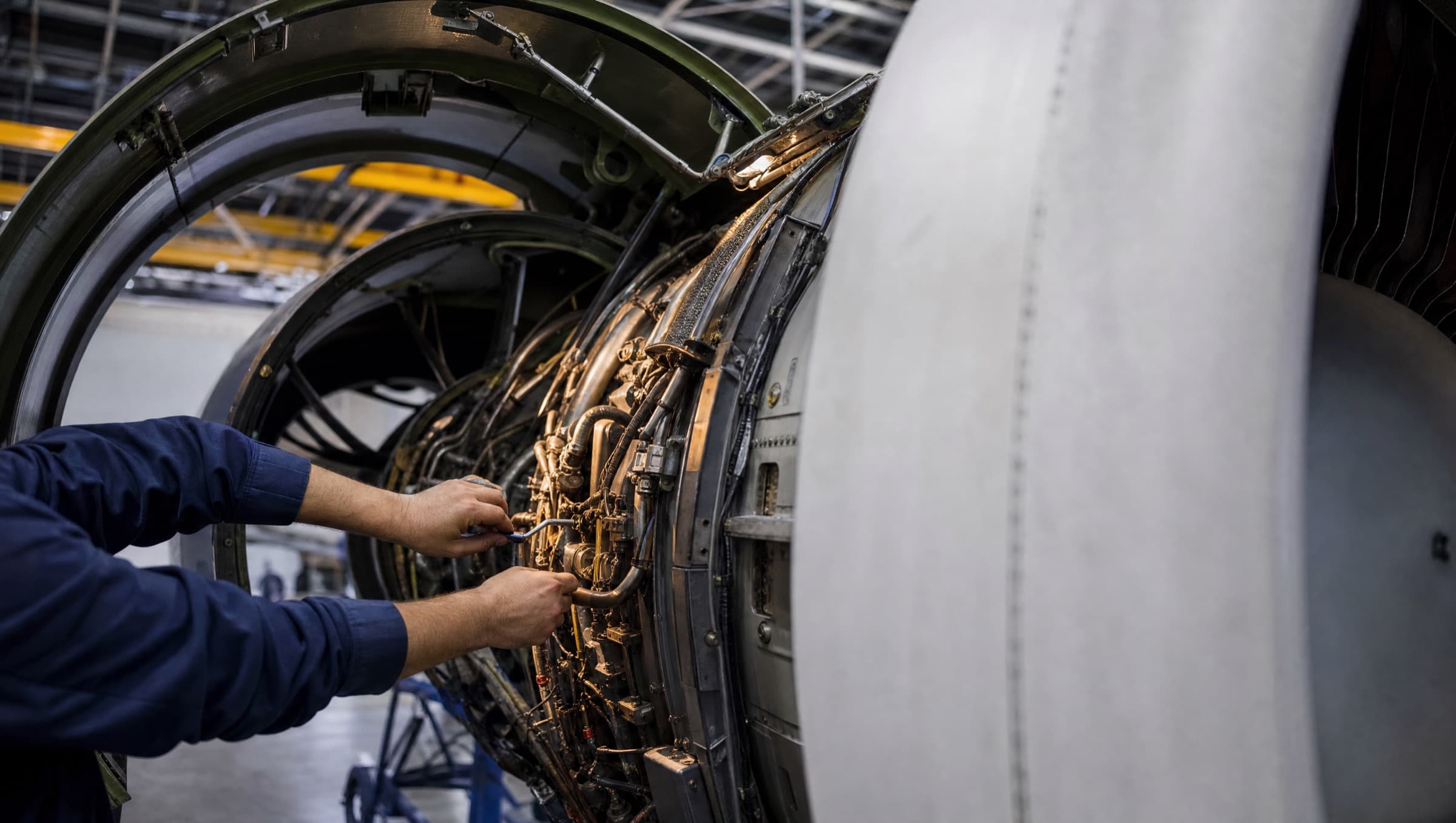 Technician working inside an open engine cowling during a base check