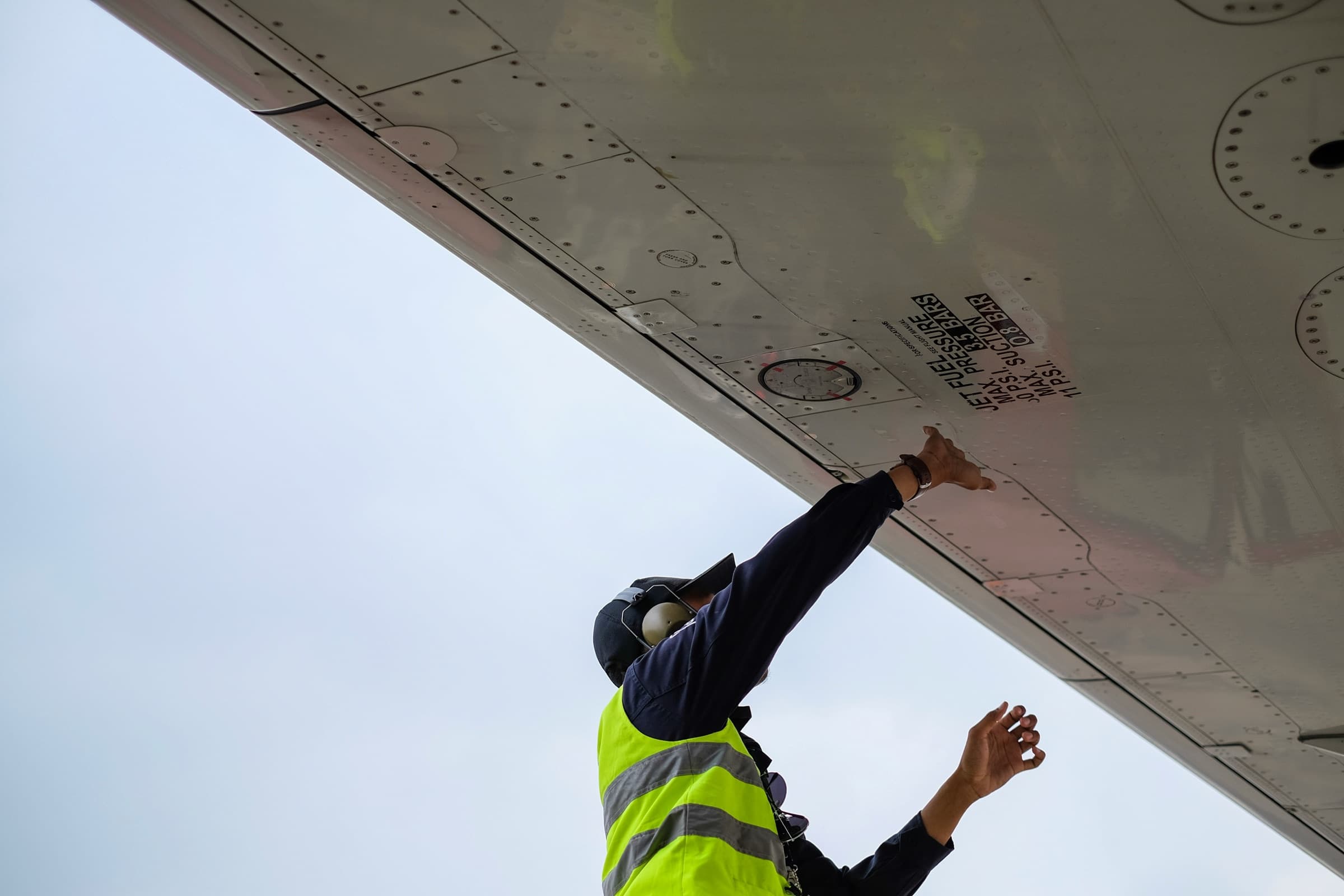 Technician inspecting the underside of an aircraft wing